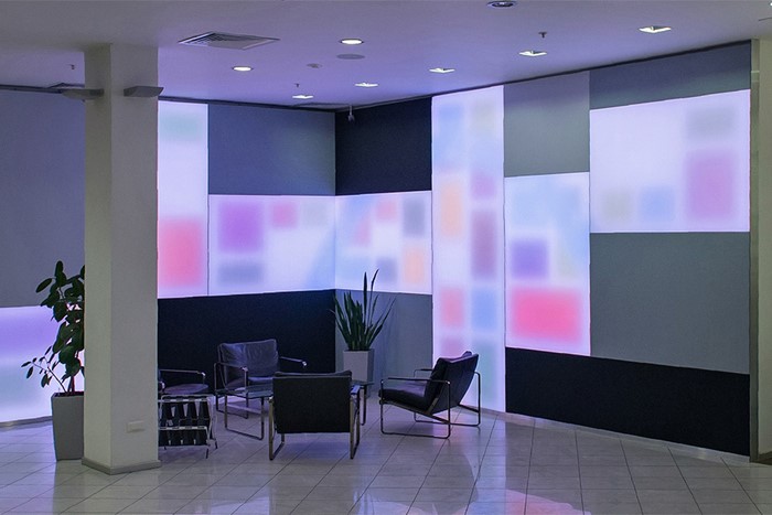 Lysende stofpaneler med firkanter i forskellige farver bag loungeområde